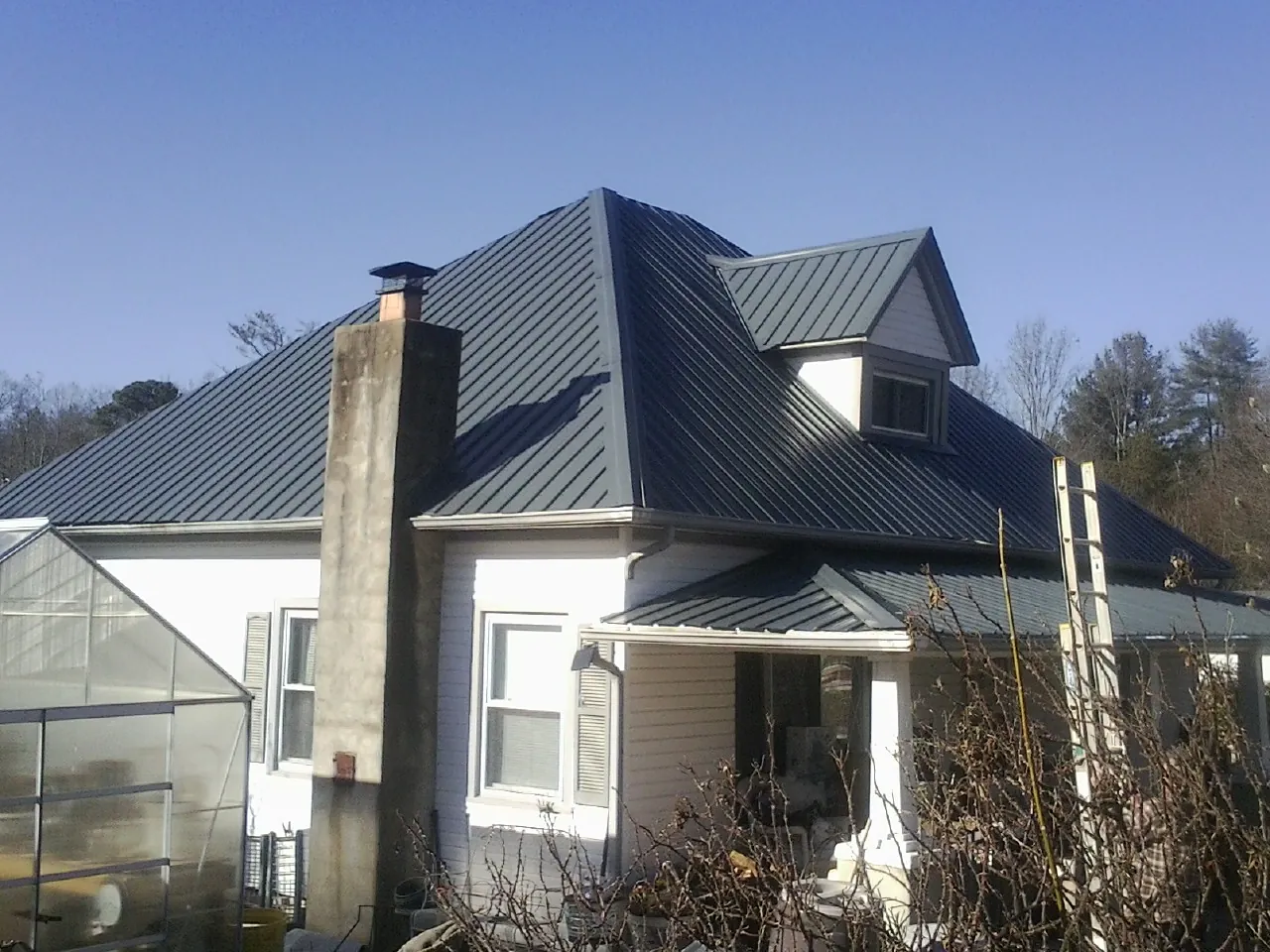 Dark blue standing seam metal roof on a white farmhouse with dormer — Slate & Tile Roof Repair by Roofing Brothers in Sandy Hook
